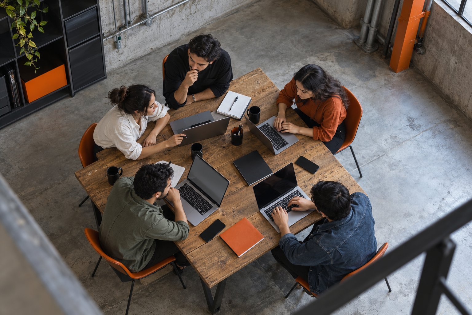 Grupo pequeño trabajando con laptops en un taller, visto desde arriba