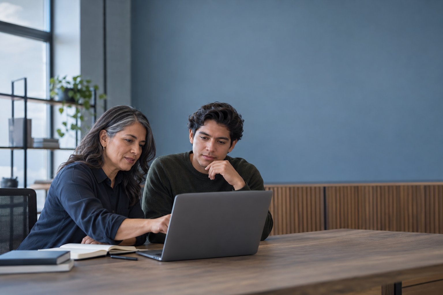 Una persona con experiencia revisando el trabajo de alguien joven en una laptop